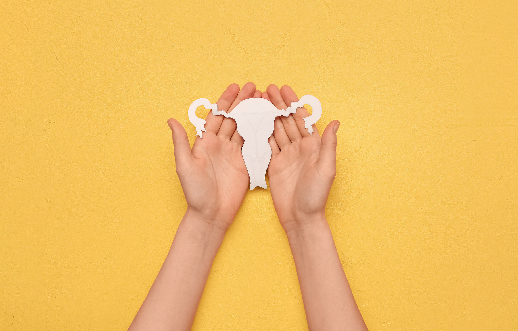 Woman with Paper Uterus on Yellow Background. Hormones Concept